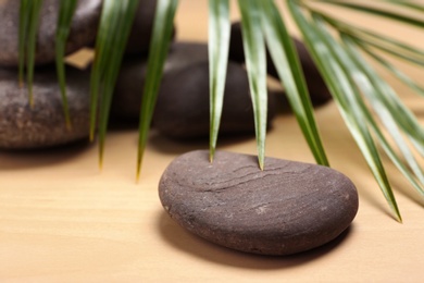 Photo of Spa stones with palm leaf on wooden background