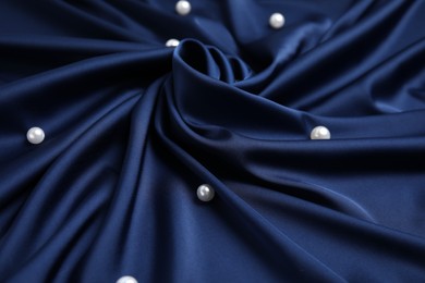 Photo of Many beautiful pearls on delicate dark blue silk, closeup