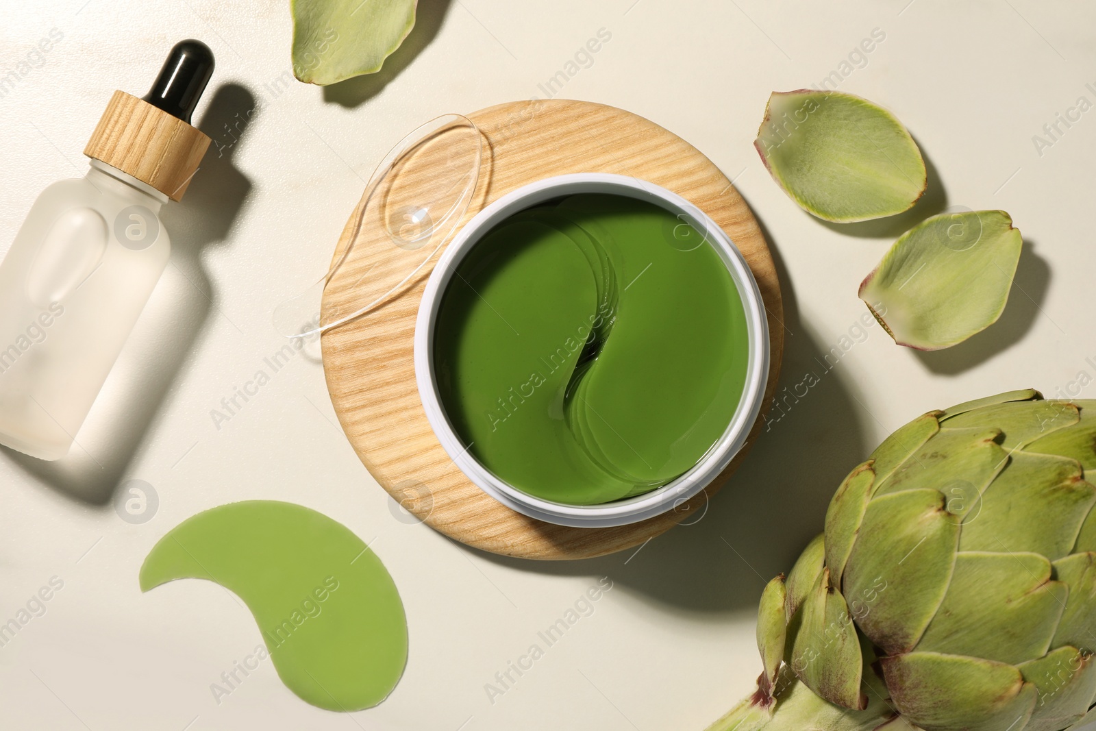 Photo of Package of under eye patches, cosmetic product and artichoke on white marble table, flat lay