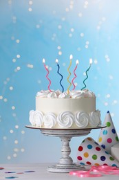 Birthday cake with burning candles and decor on white table against blurred festive lights