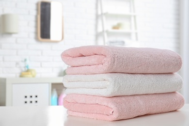 Photo of Stack of fresh towels on table in bathroom. Space for text