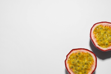 Photo of Halves of passion fruit (maracuya) on white background, flat lay. Space for text
