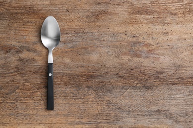 Photo of Clean empty table spoon on wooden background, top view. Space for text