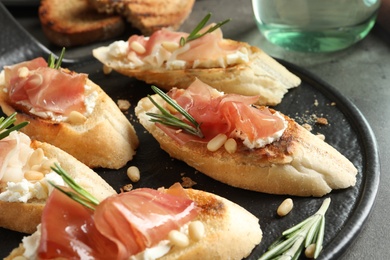 Tasty bruschettas with prosciutto and cream cheese served on table, closeup