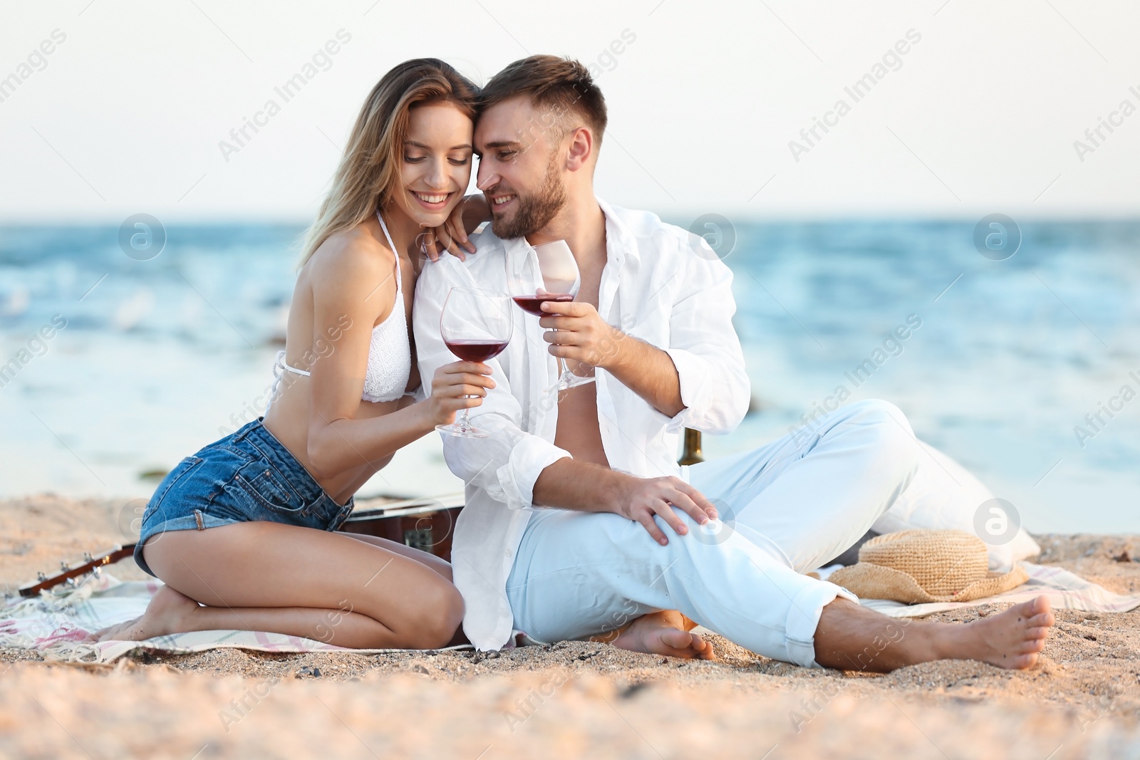 Photo of Young couple with glasses of wine on beach