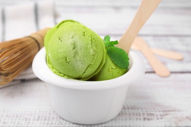 Tasty matcha ice cream in bowl on white wooden table, closeup