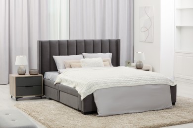 Photo of Stylish bedroom in soft light colors with comfortable bed and bedside tables. Interior design