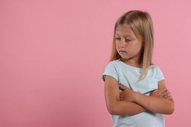 Resentful girl with crossed arms on pink background. Space for text