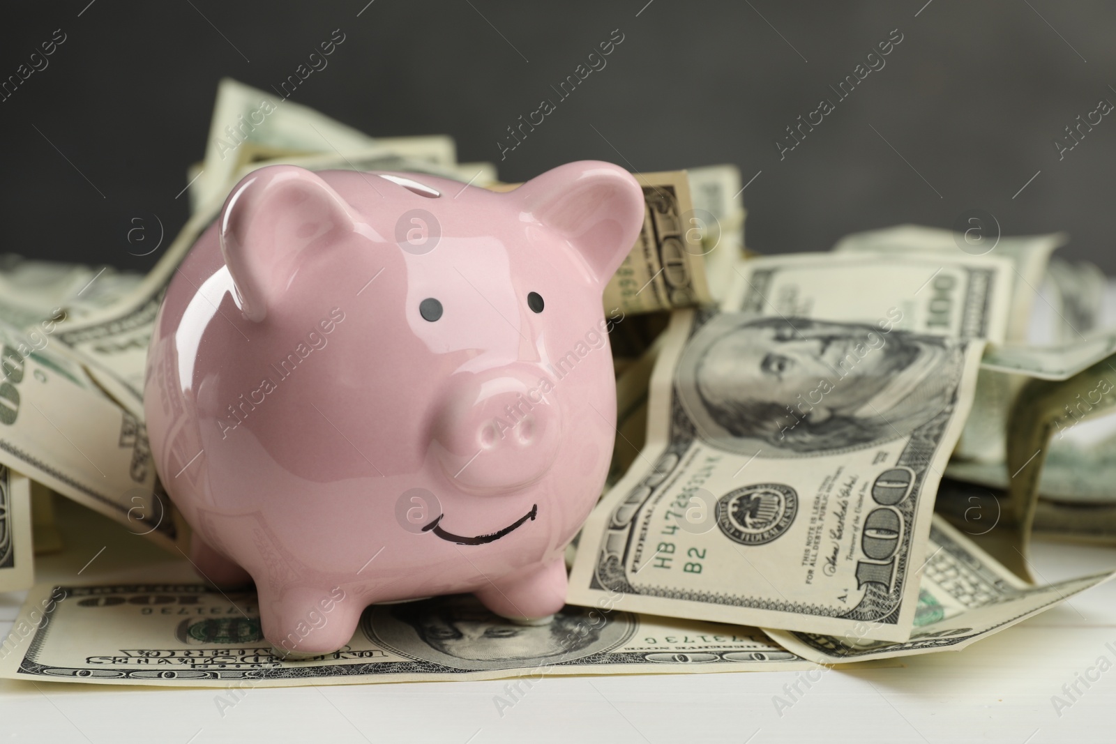 Photo of Money exchange. Dollar banknotes and piggy bank on white wooden background, closeup