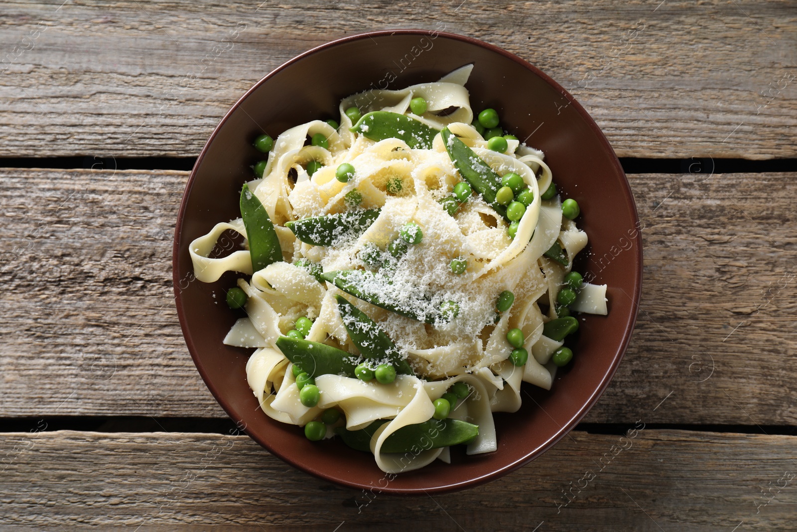 Photo of Delicious pasta with green peas and cheese on wooden table