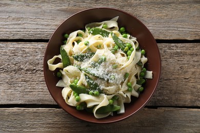 Photo of Delicious pasta with green peas and cheese on wooden table