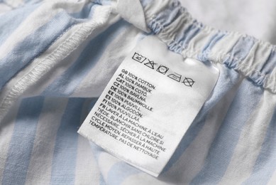 Photo of Clothing label on beautiful striped garment, closeup