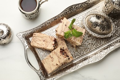 Photo of Tasty chocolate halva served on white marble table, flat lay