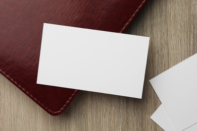 Photo of Blank business cards and notebook on wooden table, flat lay. Mockup for design