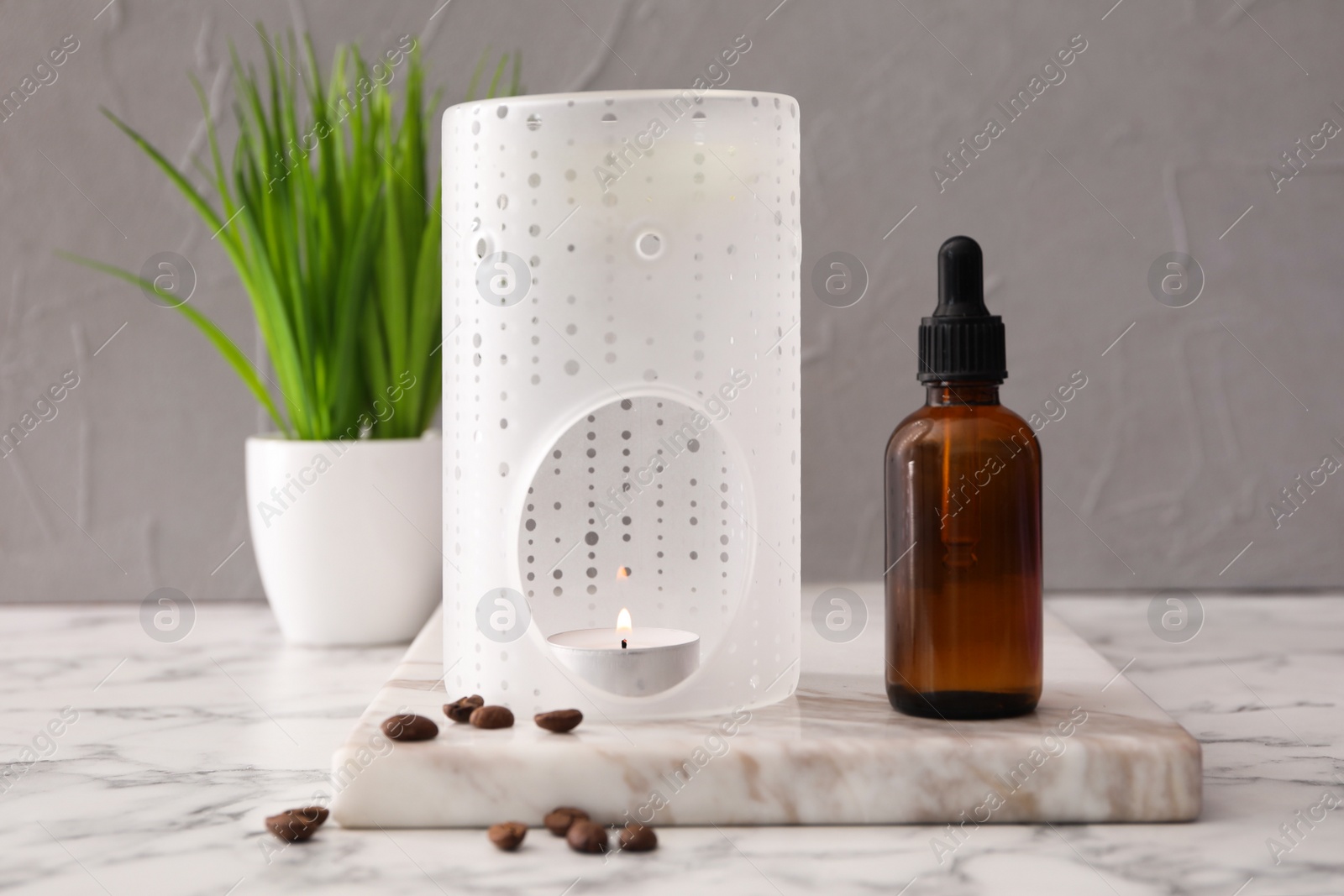 Photo of Aroma lamp and coffee essential oil on white marble table