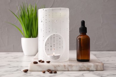 Aroma lamp and coffee essential oil on white marble table