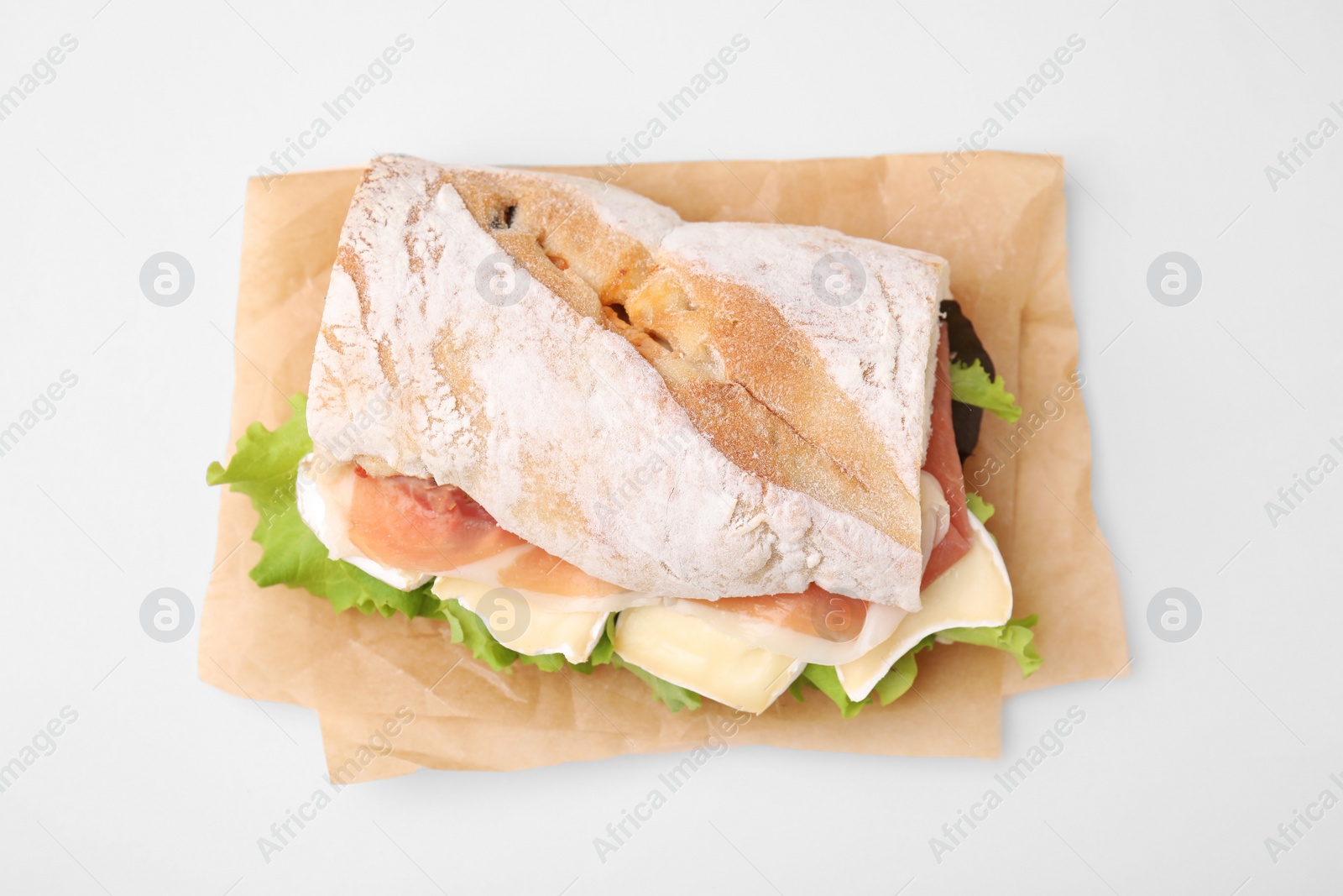 Photo of Tasty sandwich with brie cheese and prosciutto on beige background, top view