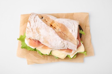 Tasty sandwich with brie cheese and prosciutto on beige background, top view