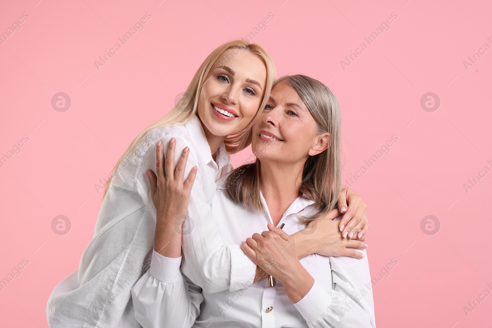 Photo of Family portrait of young woman and her mother on pink background