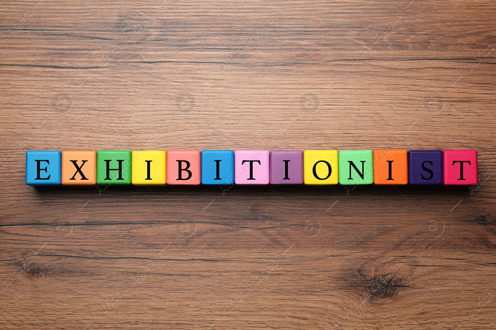 Photo of Word EXHIBITIONIST made with colorful cubes on wooden table, flat lay
