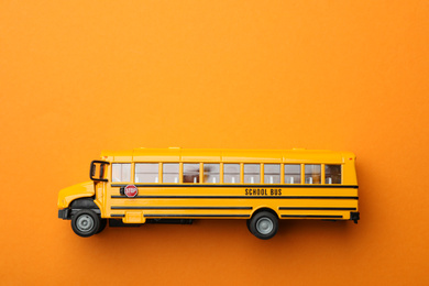 Photo of Yellow school bus on orange background, top view with space for text. Transport service