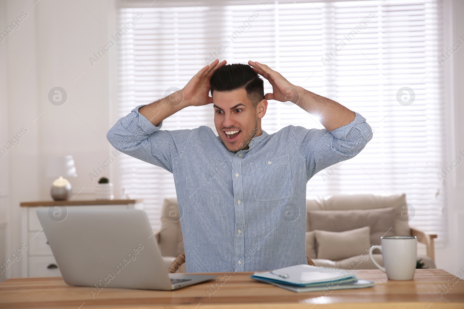 Photo of Emotional man participating in online auction using laptop at home