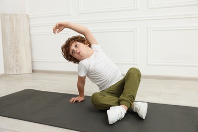 Boy doing gymnastic exercises on mat indoors