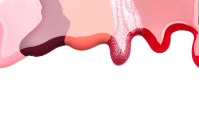 Colorful nail polishes spilled on white background