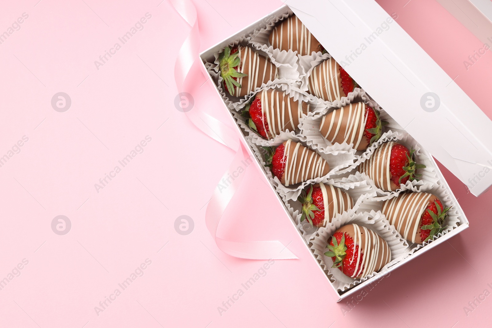 Photo of Box with delicious chocolate covered strawberries on pink background, top view. Space for text