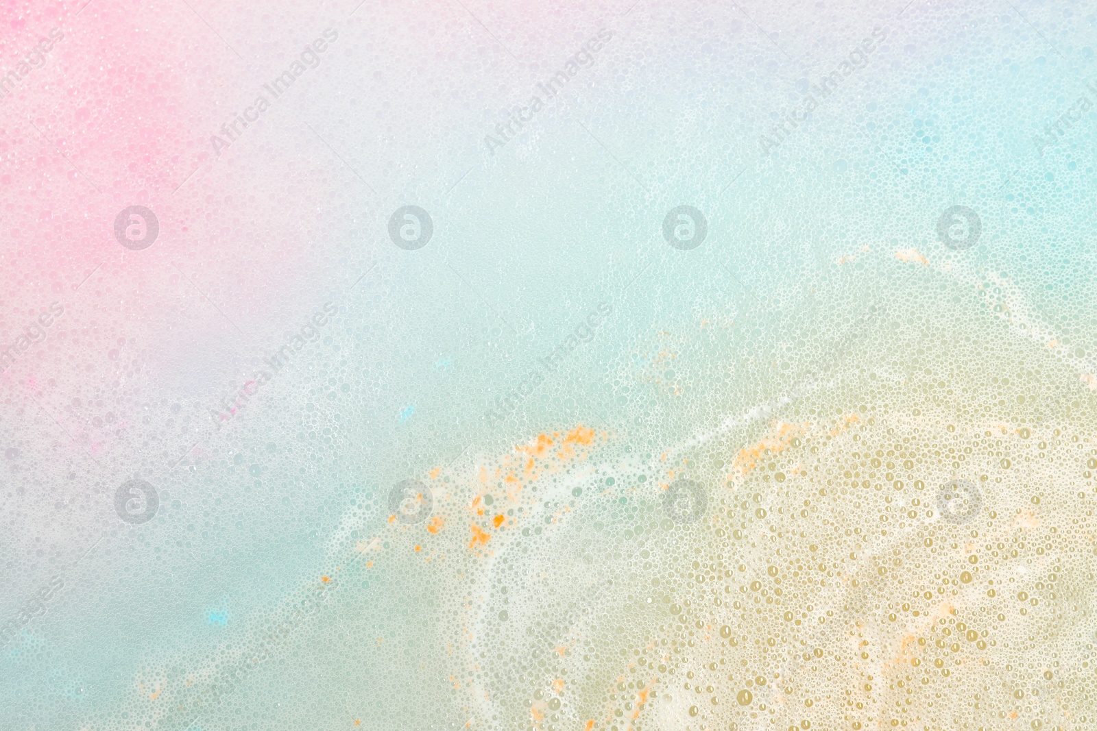 Photo of Colorful foam after dissolving bath bomb in water, closeup