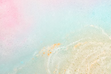 Photo of Colorful foam after dissolving bath bomb in water, closeup