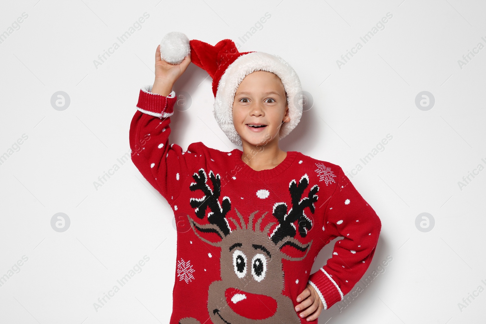 Photo of Cute little boy in Christmas sweater and hat on white background