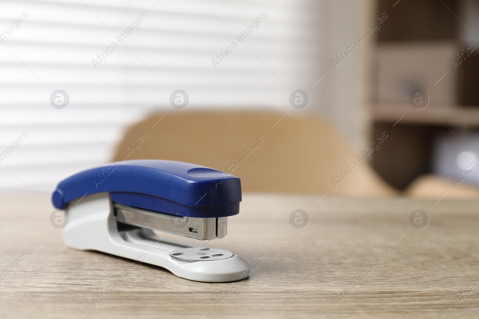 Photo of Bright stapler on wooden table indoors, closeup. Space for text