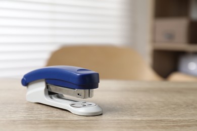 Photo of Bright stapler on wooden table indoors, closeup. Space for text