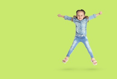 Cute girl jumping on yellowish green background, space for text