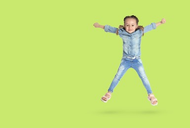 Image of Cute girl jumping on yellowish green background, space for text