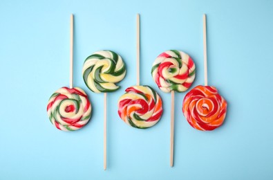 Photo of Many colorful lollipops on light blue background, flat lay