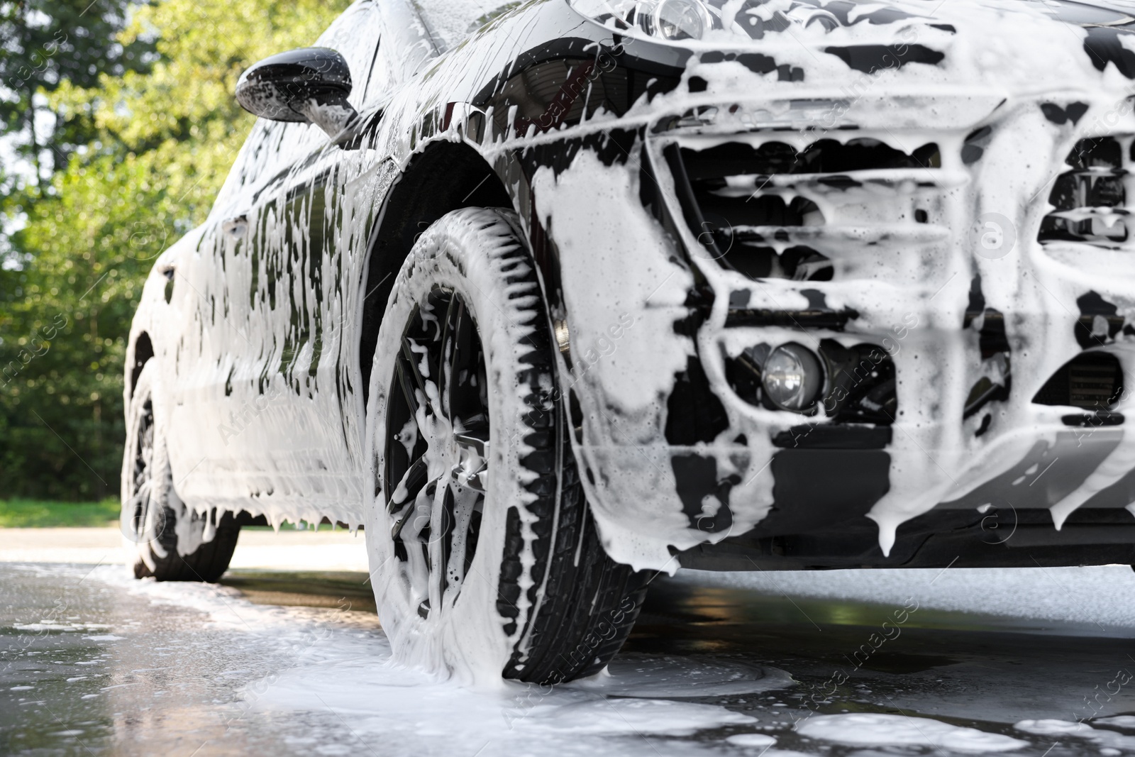 Photo of Auto covered with cleaning foam at outdoor car wash