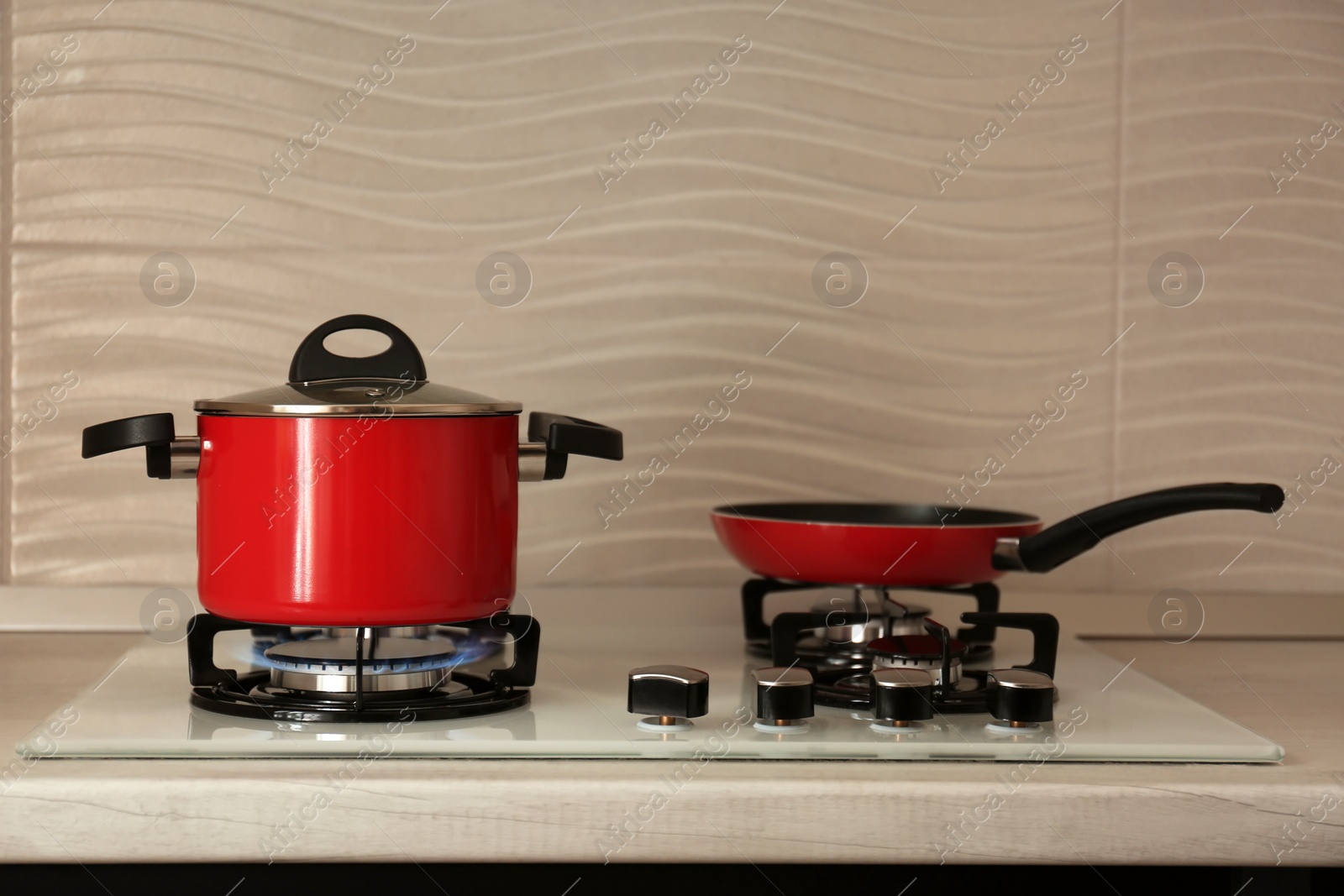 Photo of Red pot and frying pan on modern gas stove. Space for text