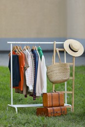 Photo of Clothing rack with different garments in yard. Garage sale