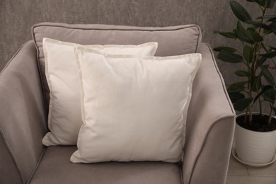 Photo of Soft pillows on grey armchair in room