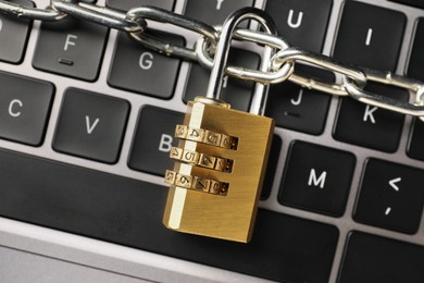 Photo of Cyber security. Padlock with chain on laptop, top view