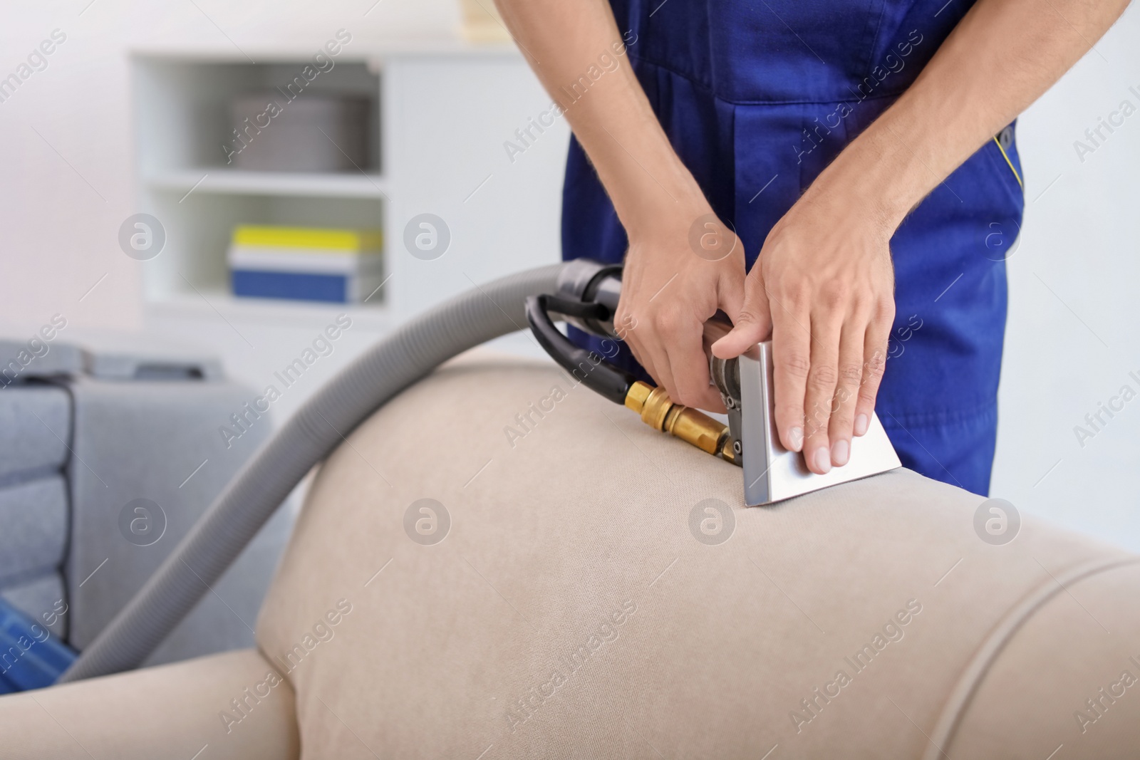 Photo of Dry cleaning worker removing dirt from sofa indoors