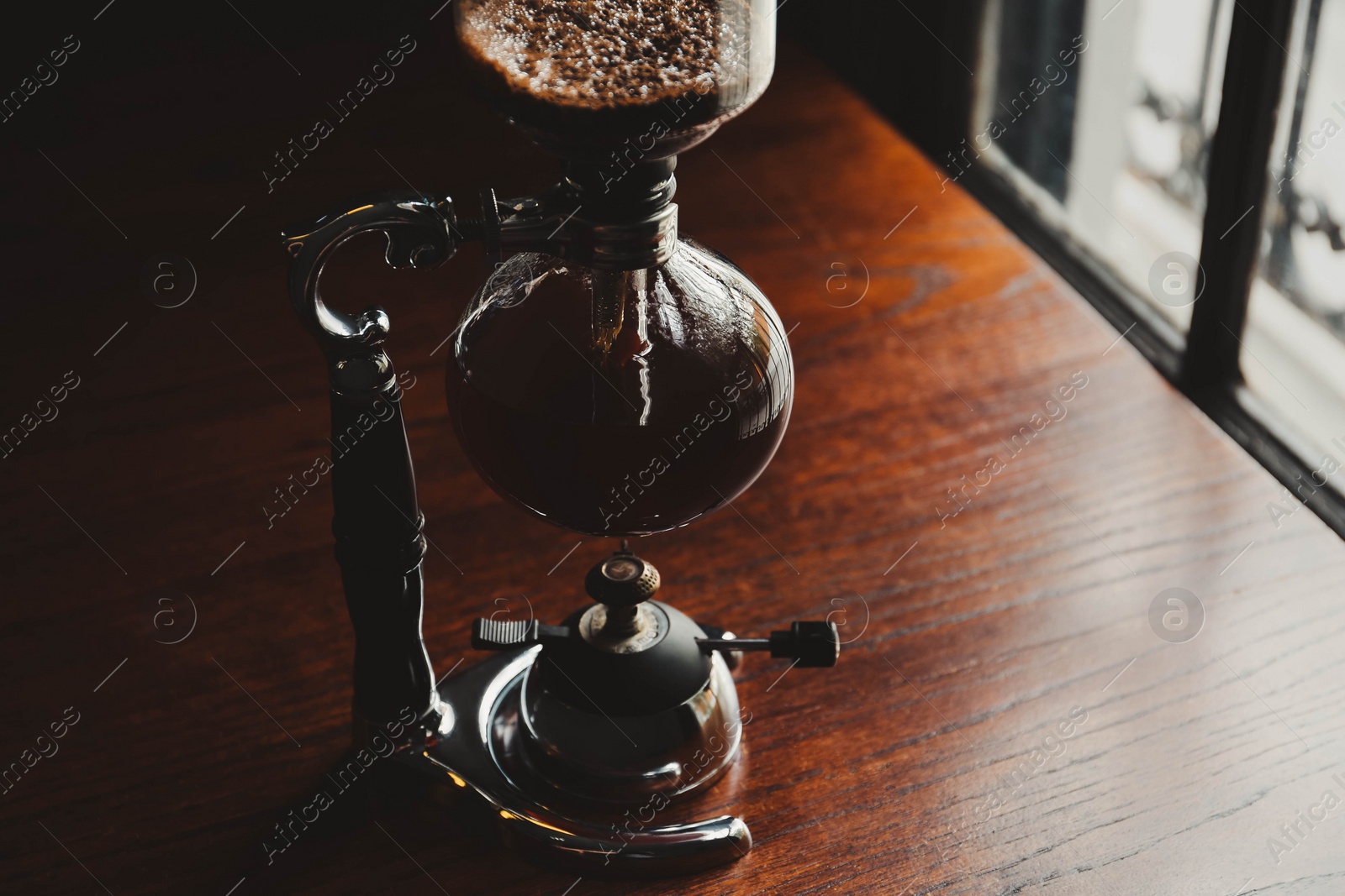 Photo of Vacuum coffee maker on wooden table in cafe