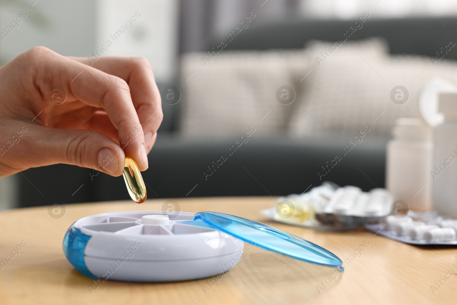 Photo of Woman with pills and organizer at light wooden table, closeup