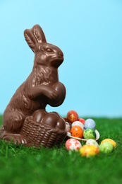 Photo of Chocolate Easter bunny and eggs on green grass