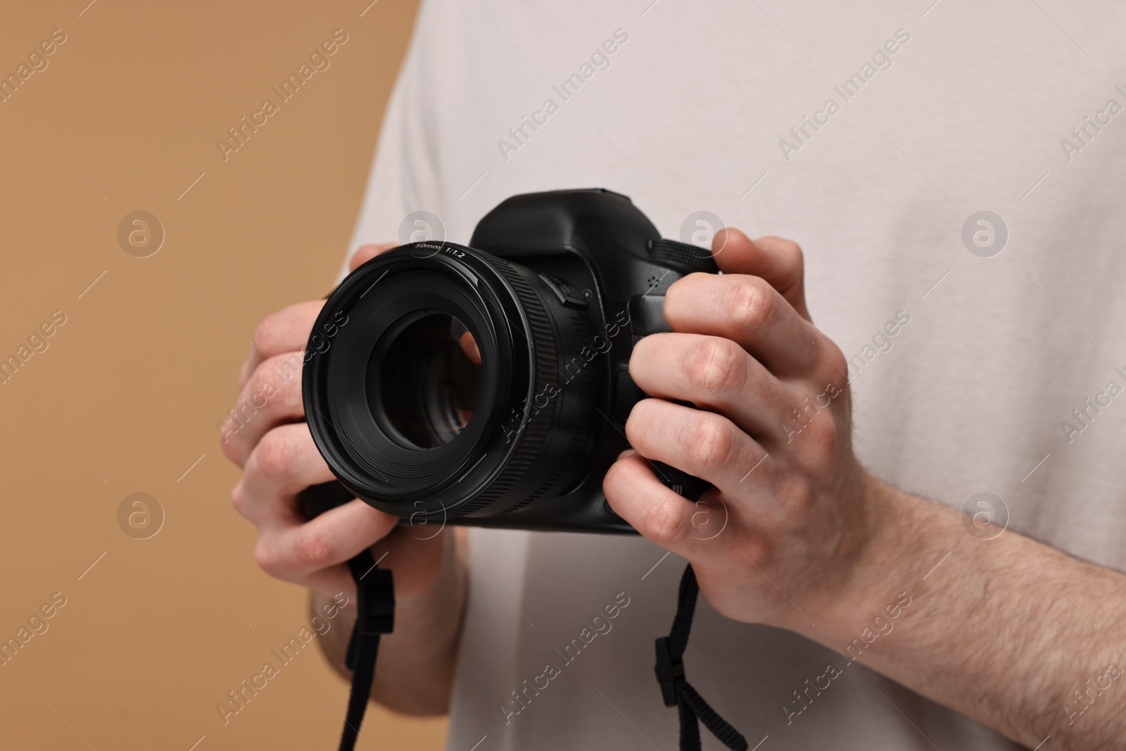 Photo of Photographer holding camera on beige background, closeup