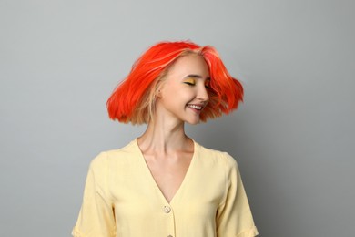 Photo of Beautiful young woman with bright dyed hair shaking head on light grey background