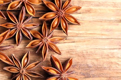 Aromatic anise stars on wooden table, flat lay. Space for text