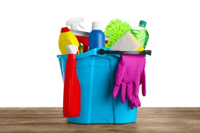 Bucket with many different car wash products on wooden table against white background